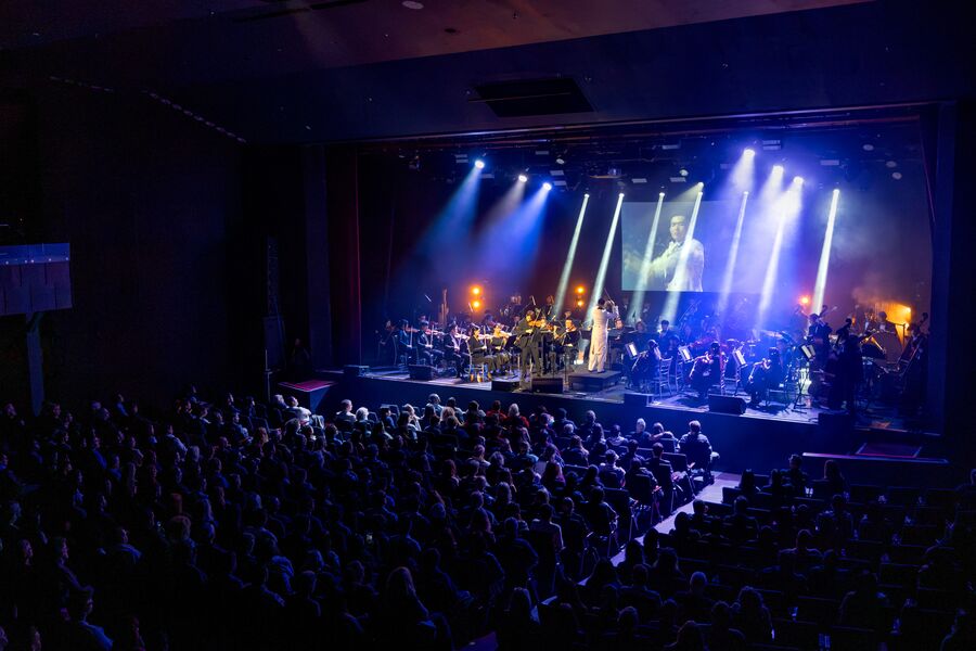 The orchestra under blue stage lights at the Queen Elizabeth Theatre, October 2026