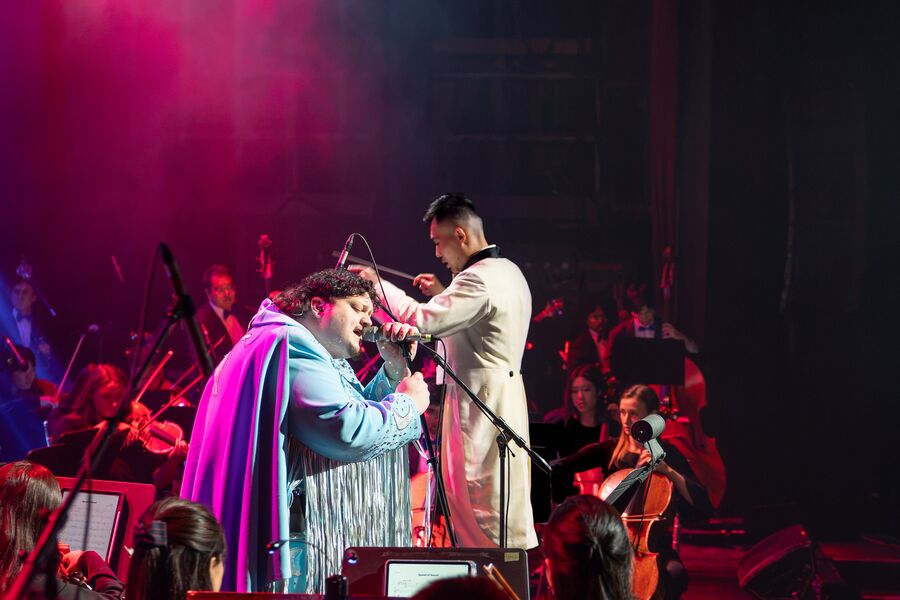 TALK singing beside conductor Yuang Chen in red stage light, October 2026