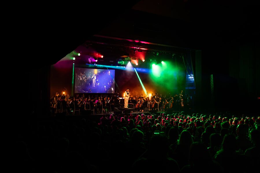A full Queen Elizabeth Theatre watching the orchestra under green and red lights, October 2026