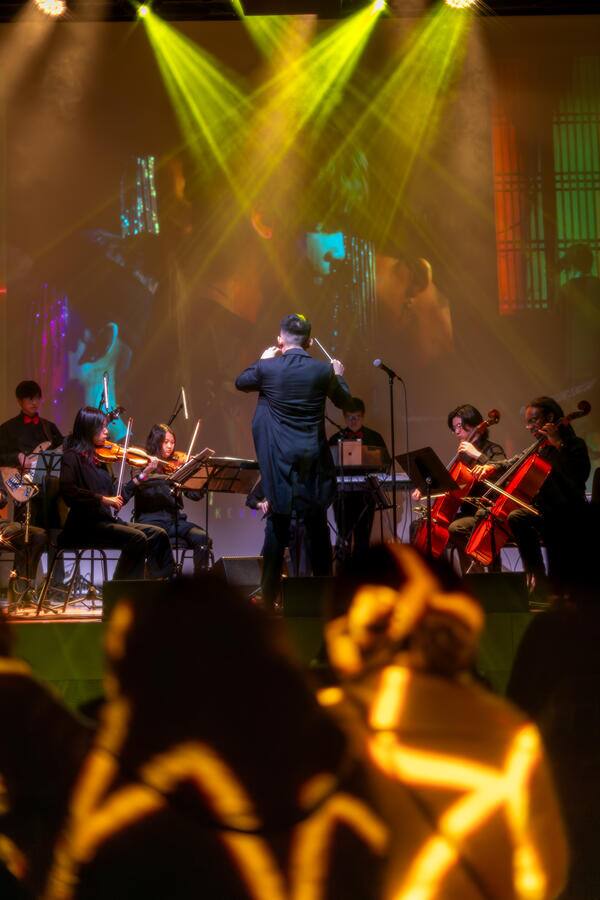 The orchestra under stage lighting at Melodic Eruption